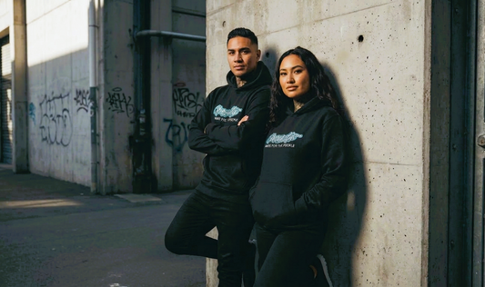 Two people (male and female) wearing the black you matter hoodie leaning against wall in urban alley way
